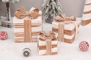 Detail of three cream and khaki velvet Christmas gift boxes with textured fabric and bows