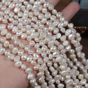 Hand holding high-luster white baroque freshwater pearls for handmade jewelry DIY