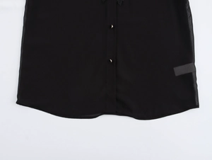 Detailed macro view of the hem and metallic buttons on a black chiffon shirt