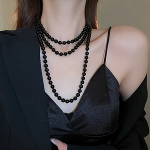 Detail of elegant black layered pearl necklace worn with a stylish blazer and black dress