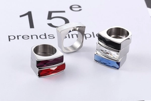 Close-up of geometric titanium steel rings with rectangular colorful zircon and shell insets