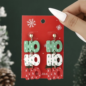 Detail shot of Christmas HO HO HO earrings with festive red white and green patterns