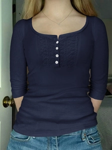 Detail view of navy blue long sleeve top with white buttons and delicate lace trim accents