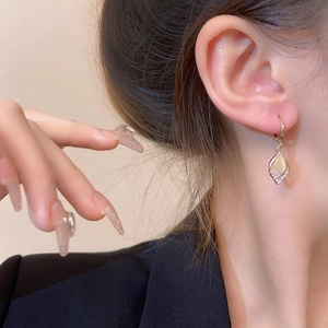 Close-up of golden cat-eye stone teardrop earrings featuring sparkling micro-inlaid zircon