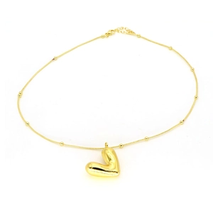 Detalle de un colgante de corazón dorado pulido en una cadena de serpiente con cuentas