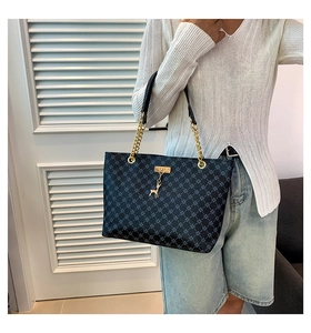 Dettaglio della borsa tote blu navy con motivo a rombi e accessorio pendente a cervo d'oro