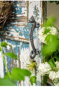 Close-up of seahorse cast iron handle on rustic blue wood with white flowers