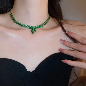Detail of elegant gold necklace with green leaf-shaped zircon crystals on model's neck