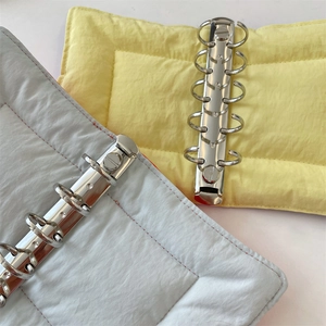 Close-up of a 6-ring binder notebook with quilted fabric cover and silver metal rings