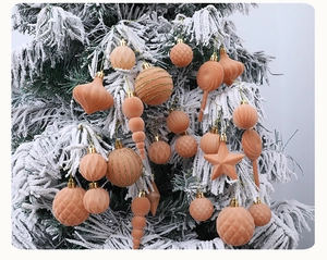 Nahaufnahme pfirsichfarbener beflockter Weihnachtskugeln an einem schneebedeckten Tannenast