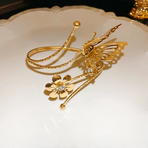 Close-up of golden leaf arm cuff with hollow butterfly and zircon flower on ceramic plate