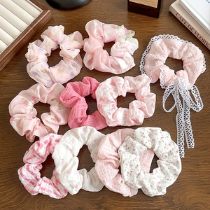 Set of 10 pink floral scrunchies with lace ribbons and bows on a wooden background