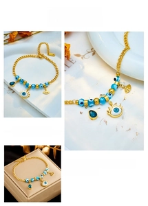Macro detail of gold chain bracelet with blue evil eye beads and water drop pendants