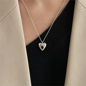 Minimalist sterling silver heart necklace with black onyx gemstone worn by a model