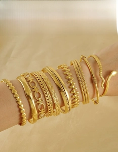 Detail of stacked 18K gold plated stainless steel bracelets in various textures