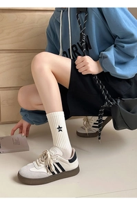 Close-up of black striped crew socks with letters paired with retro sneakers