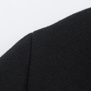 Close-up of black wool blend fabric showing fine herringbone weave and soft texture