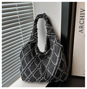 Detailed view of dark grey denim tote bag featuring quilted texture and frayed edges