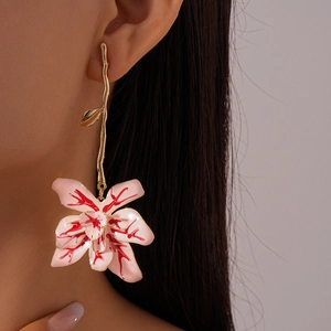Detail of pink floral oil-drop earrings with gold stem worn by a model in soft light