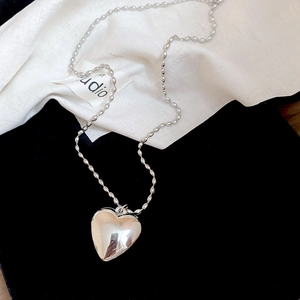 Detail of silver heart pendant necklace with high-polish finish on pearl bead chain