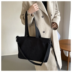 Detail of black corduroy tote bag featuring vertical texture and adjustable shoulder strap