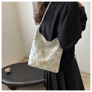 Detail of elegant gold and blue butterfly embroidery on a cream shoulder bucket bag
