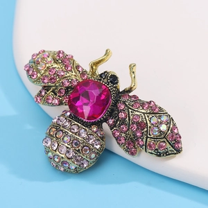 Macro shot of bee brooch with pink crystals and magenta gemstone on gold metal