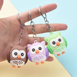 Handheld view of cartoon owl keychains in brown, purple and green with metal rings