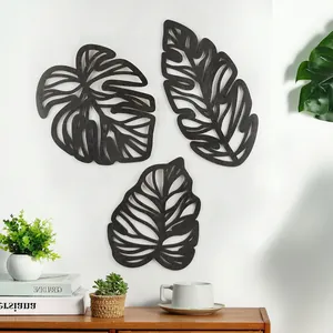 Detail of three black tropical laser-cut monstera wooden wall art panels in a modern room