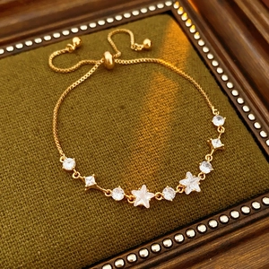 Detail of adjustable gold star and round zircon bracelet on green velvet display base