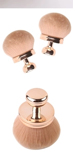 Close-up of portable mushroom head powder brush with soft beige bristles and rose gold handle