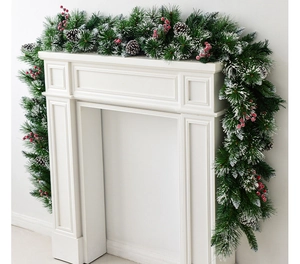 Detail of a snow-flocked Christmas garland with red berries on a white fireplace