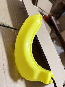 Detailed view of a bright yellow plastic banana protector case in a storage setting