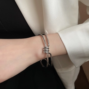 Detailed view of silver twisted knot cuff bracelet on wrist with elegant suit