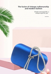 Royal blue satin evening bag with rhinestone-encrusted handle on pink display blocks