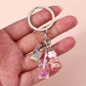 Detail of keychain featuring miniature milk tea cup and wish bottle charms in hand