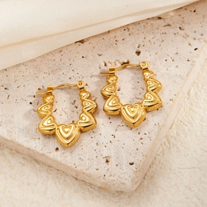 Macro shot of 18K gold plated stainless steel hoop earrings with relief heart patterns