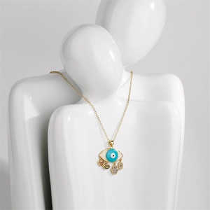 Golden necklace with blue evil eye pendant and heart charms on a white mannequin