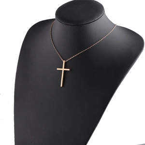 Macro detail of rose gold cross pendant on black bust with polished metal finish