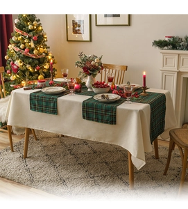 Close-up of green plaid table runner and beige tablecloth in cozy Christmas setting