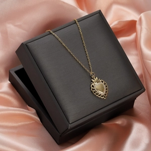 Detailed shot of golden heart crown pendant with rubies on a black jewelry box