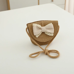 Close-up of khaki straw shoulder bag with a red polka dot bow and lace trim for kids