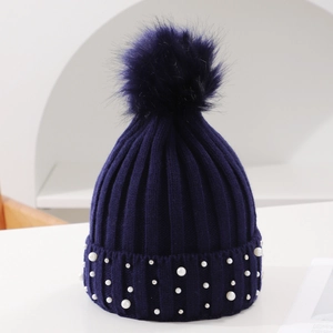 Navy blue knit hat with fluffy pompom and elegant pearl beads on the folded brim