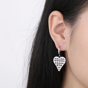 Close-up of silver hollow heart earrings with inlaid crystals on female model