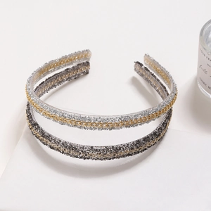 Sparkling rhinestone headband with gold chain trim on elegant white display platforms