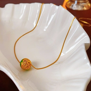 Dettaglio del motivo in metallo traforato placcato oro 18K su un pendente in vetro verde