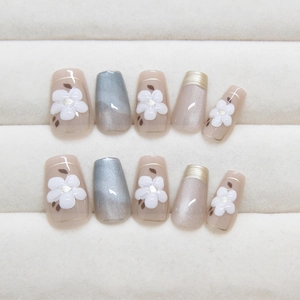 Cat eye press-on nails with 3D floral designs and gold accents in coffin shape