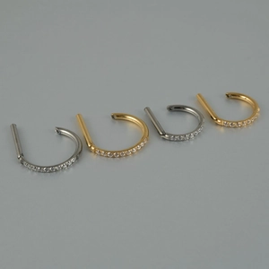 Detailed view of silver and gold titanium nose rings with cubic zirconia settings