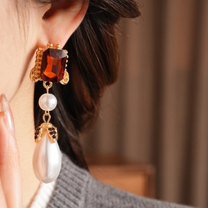 Detailed view of vintage drop earrings featuring amber gems and elegant pearls on model