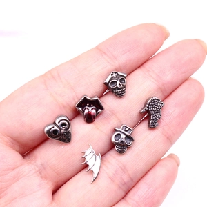 Detailed view of assorted gothic skull and bat wing jewelry studs on a hand for scale
